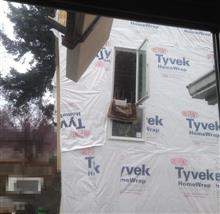crane loading drywall boards into upstairs window