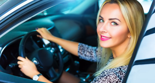 運転席に座りながら笑顔を見せる美女の画像