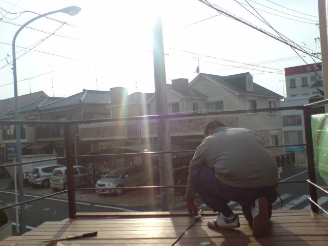 最後の1枚を貼る職人に、夕日が挿す