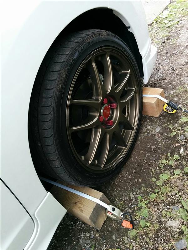 ダウンサスを組んだ時に、フィーリングでトー調整を行いましたが、一応測ってみようと思い、皆さんの整備手帳を参考にメジャーを使って写真のようにやってみました。<br />
<br />
すると!!<br />
まったくもって適正ではなくトーインが強すぎる状態（￣□￣；）！！<br />
<br />
これは早急な調整が必要です。<br />
調整は、ステアリングロッドのロックボルト（１９ｍｍ）を緩め、１４ｍｍのレンチで調整します。<br />
ステアリングロッドを伸ばせばトーイン、縮めればトーアウトですが、どうも回す方向が混乱しちゃいます。<br />
<br />
ステアリングを切らなくても、この状態でもなんとか調整ボルトに手が届きます。<br />
調整しては試走を何度か繰り返してステアリングセンターを出し、この高さ(約１０cm）の測定でトーイン4mmくらいにしました。<br />
同じ高さを出すために、角材をタイヤにこすりつけ、マスキングテープで印を付けたところで測っています。